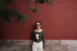 facing your fears - a woman leaning against a wall with a cup of coffee